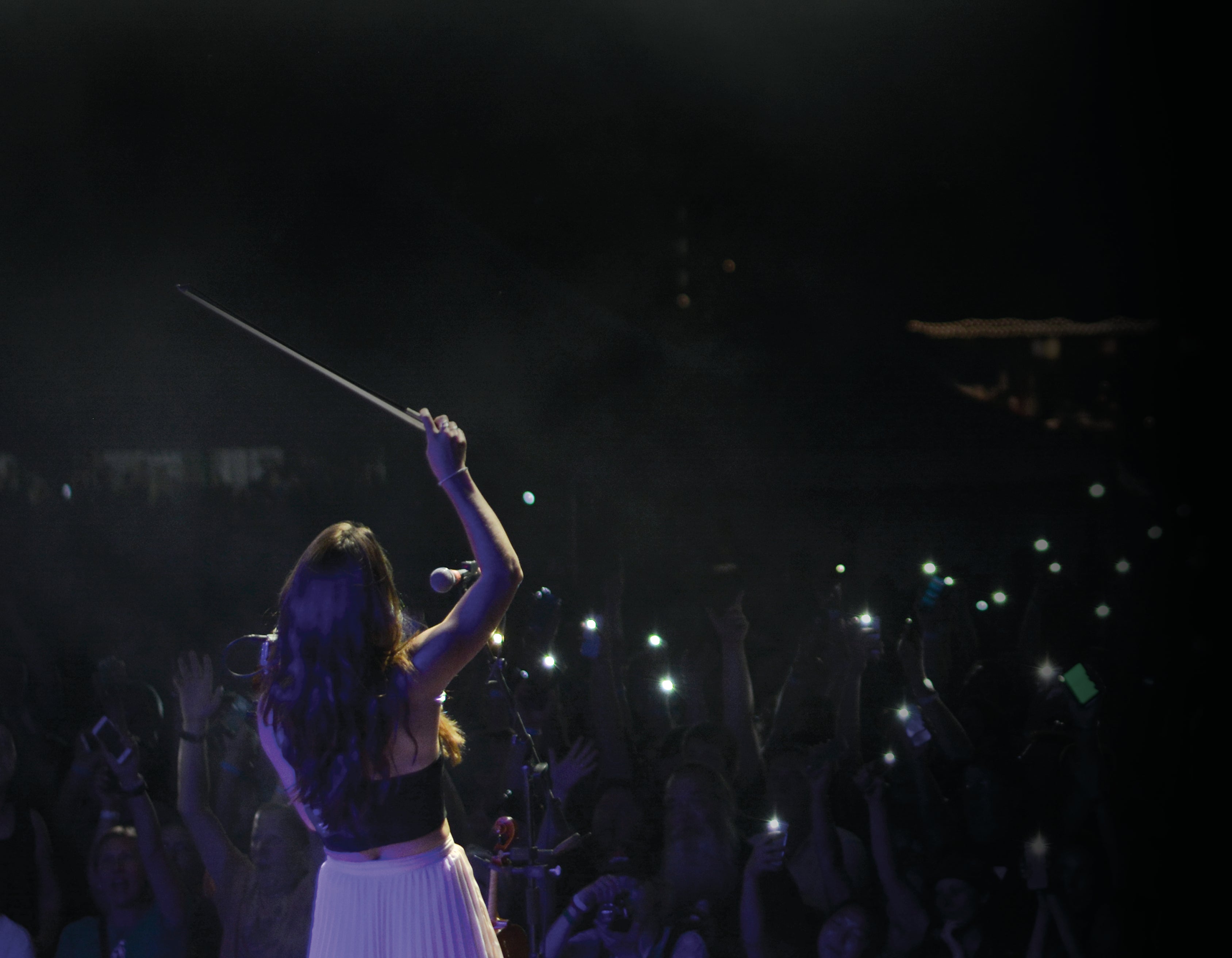 Person on stage with raised arm with a CodaBow on a dark background