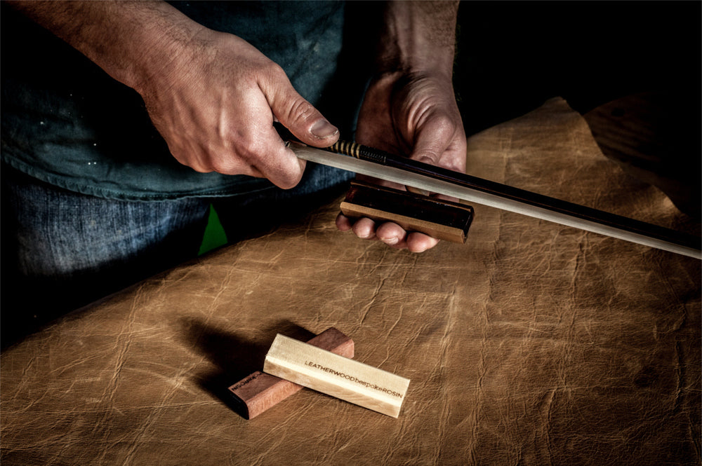 craftsman putting rosin on a bow