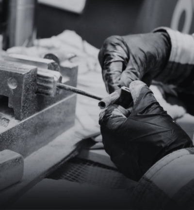 Person working with tools on a piece of metal in a workshop setting