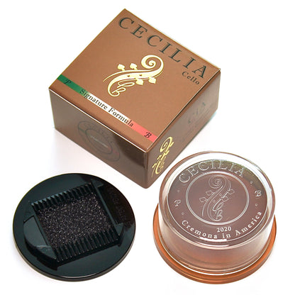 A cello rosin sits in a clear container with a brown lid and a black applicator; it’s packaged in a brown box marked "CECILIA Cello" and "Signature Formula".